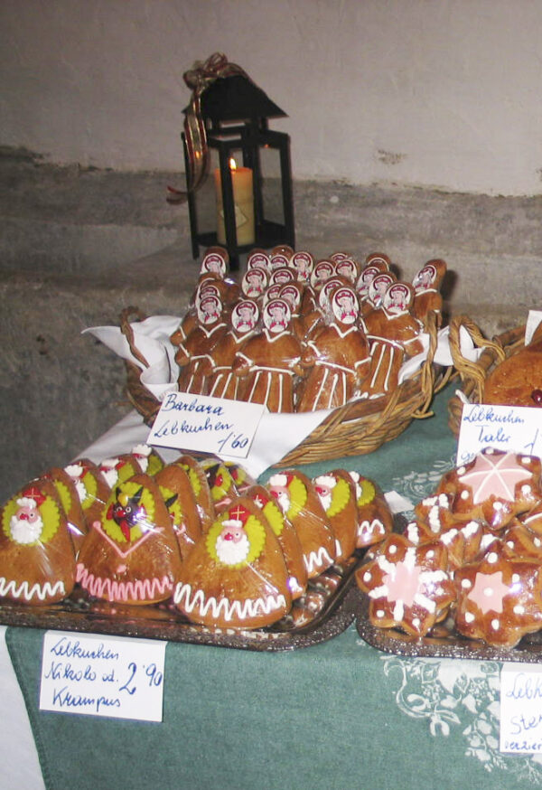 Ein Stand der Bäckerei und Konditorei Friedrich Rettig aus Matzen beim Advent im Brandlhof. Da die Hl. Barbara als Schutzpatronin der Bergleute aufgrund der Erdölförderung im Marchfeld eine große Rolle spielte, wurden am 4. Dezember Barbaralebkuchen gefertigt, links hinten sichtbar mit dem Papiergesicht.